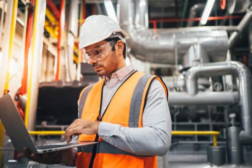 Engineer foreman using laptop controlling machine at industrial plant