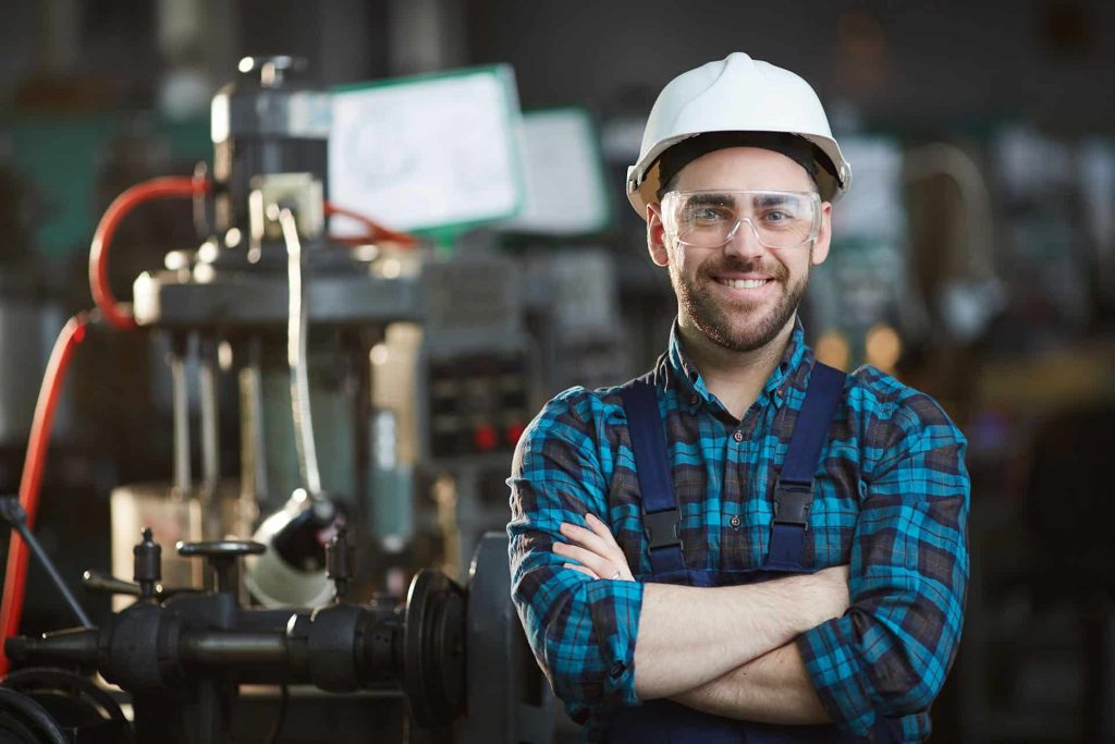 Factory worker wearing blue shirt and smiling at camera
